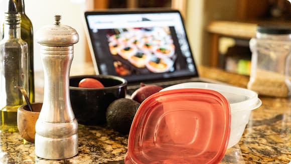 kitchen counter with ingredients and laptop with recipe on it
