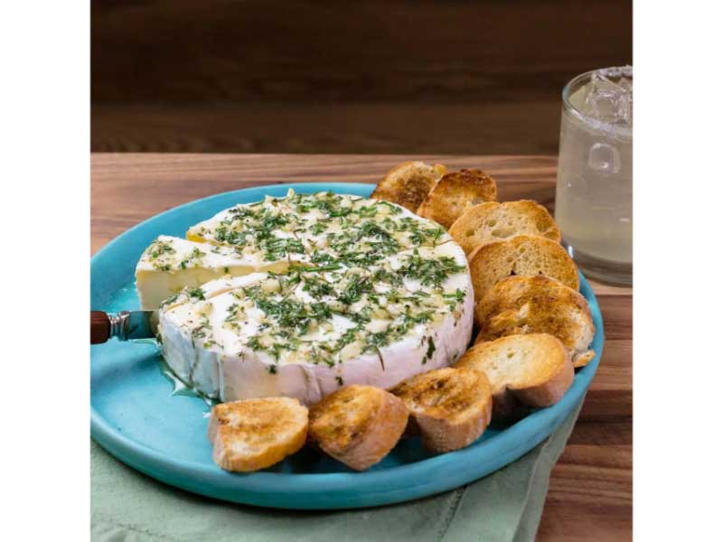 Baked Brie with Lavender Honey and Herbs on plate with a drink