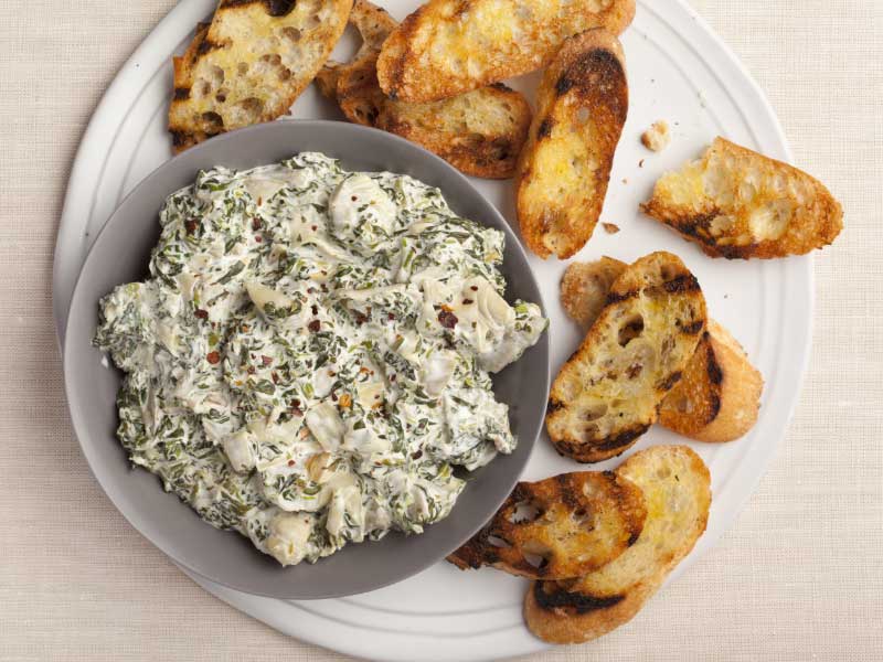 Hot spinach and artichoke dip on plate with bread